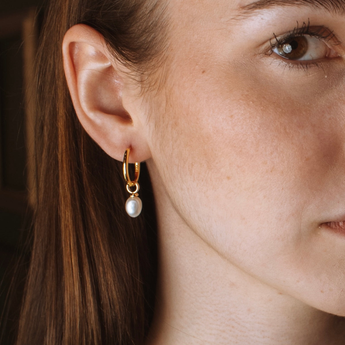 Pearl drop hoop in 18K gold vermeil on a model's ear with a freshwater pearl.