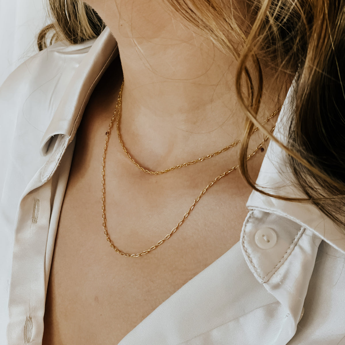 Wave chain necklace in gold filled layered on a model.