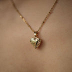 Vintage Heart locket on a model, a small engraved heart pendant on a fine chain.