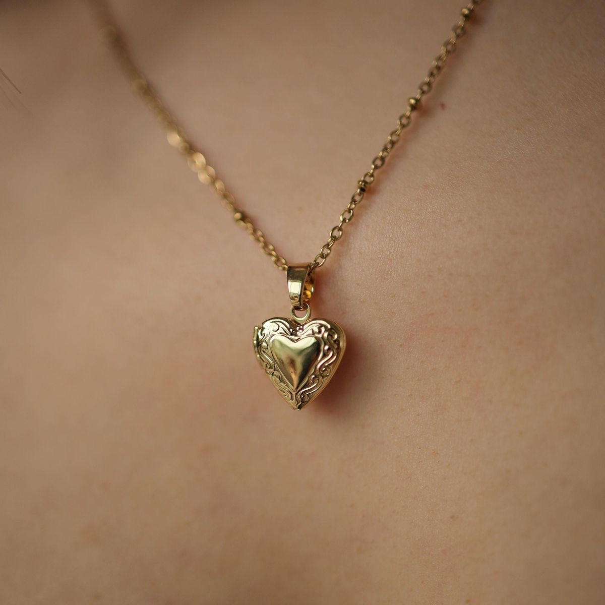 Vintage Heart locket on a model, a small engraved heart pendant on a fine chain.
