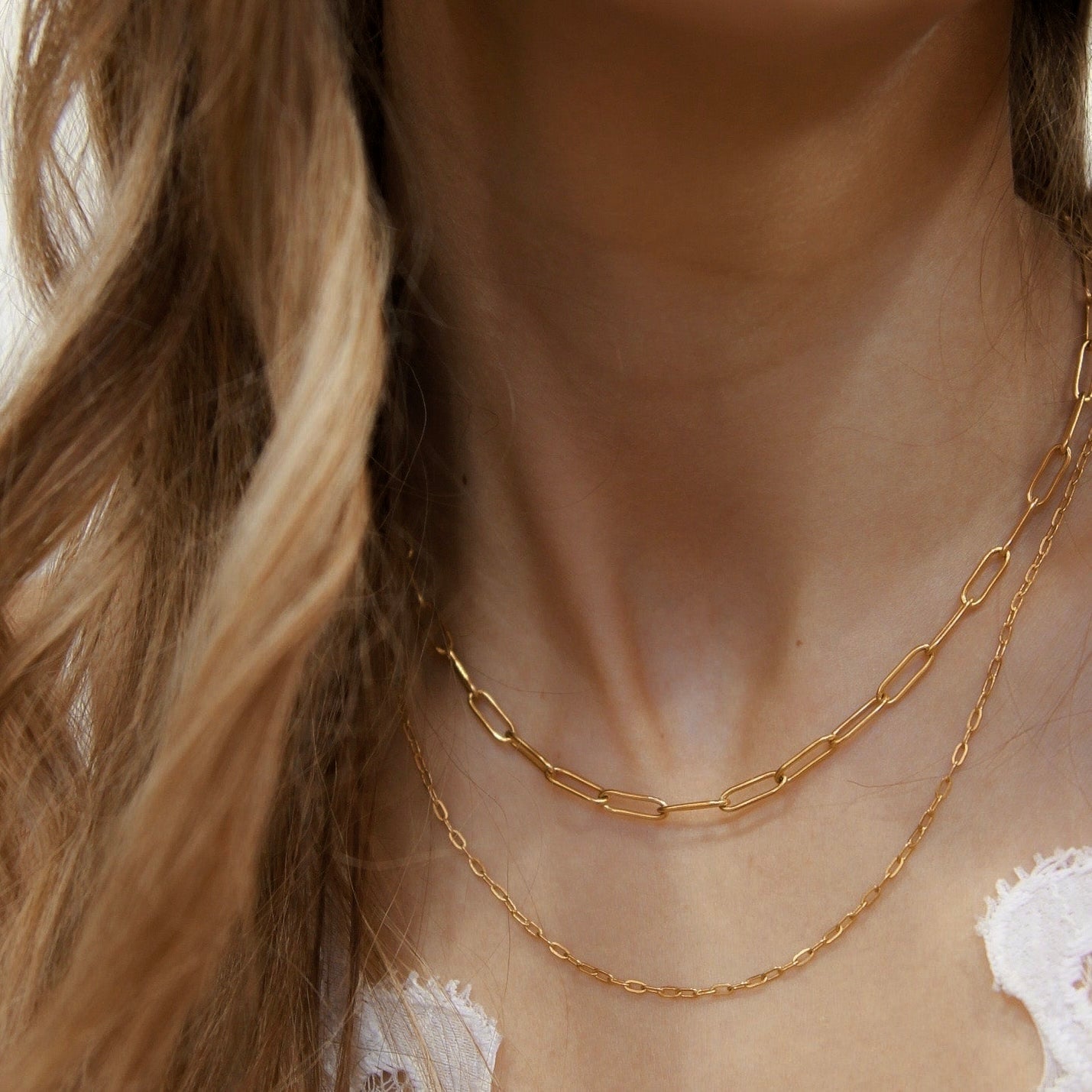 18K gold fill paperclip chain necklace with 4mm links layered with a fine gold chain on model neckline.
