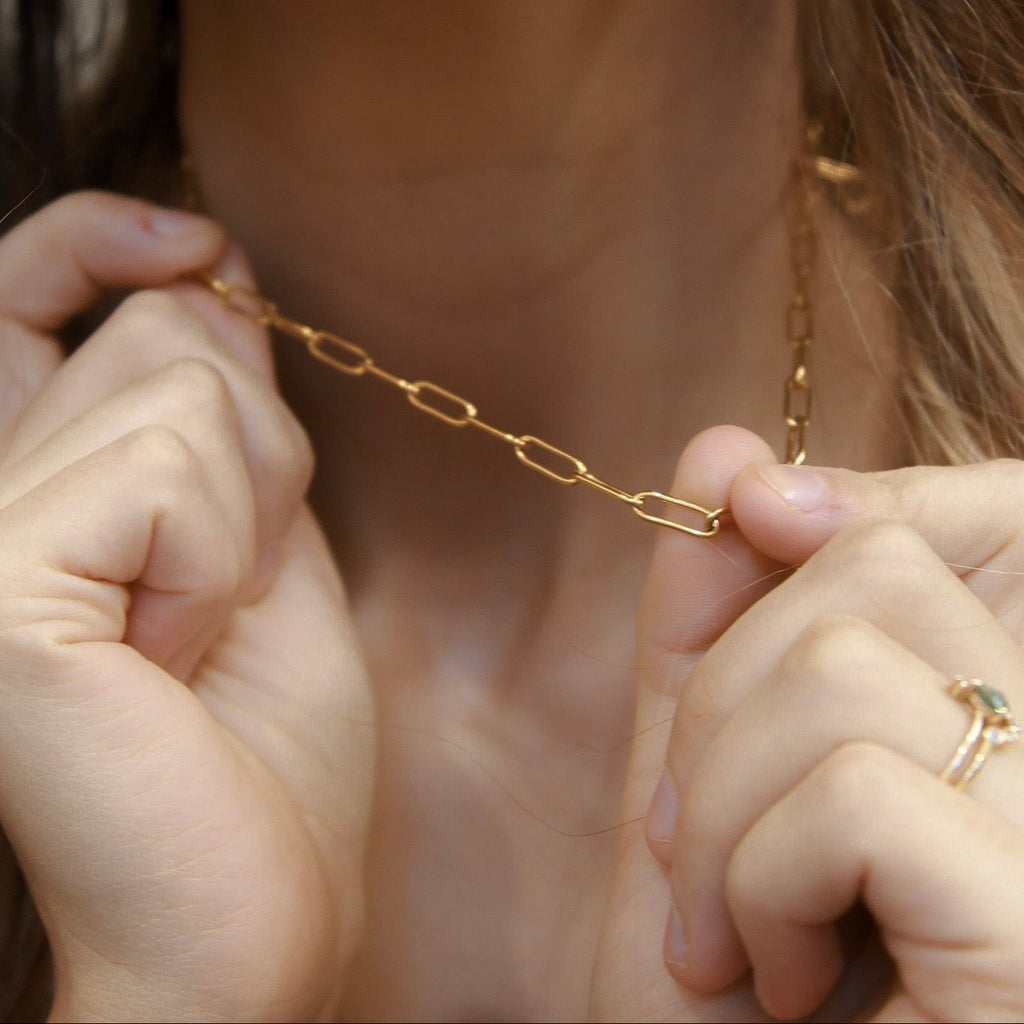 Close-up of an 18K gold fill paperclip chain necklace with elongated 4mm links held by hands.