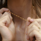 Close-up of a gold filled paperclip chain necklace with elongated 4mm links held by hands.