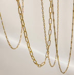Layered gold filled paperclip chain necklace styled with delicate gold chains on a neutral background.