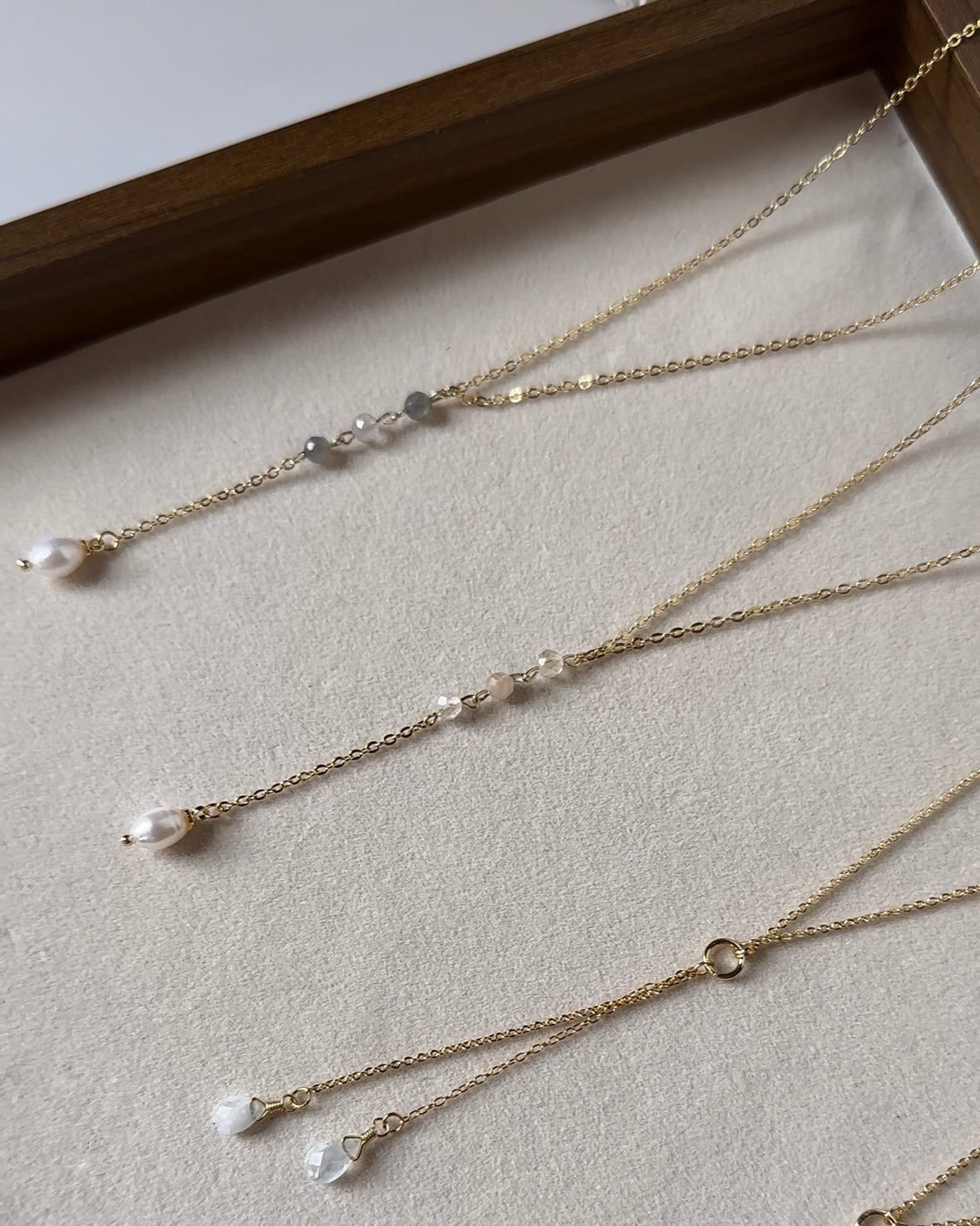 Gold filled lariat necklaces shown with labradorite and rose quartz drops, each finished with a freshwater pearl.