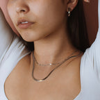 Silver-tone stainless steel Clementine herringbone chain layered with a finer chain on a model.