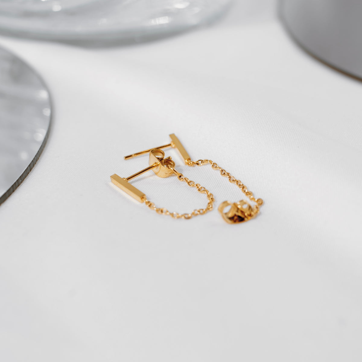 Pair of 18K gold vermeil bar chain-link stud earrings displayed over a white card, chains hanging.