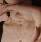 Gold filled Wave chain layered with fine chains and a pendant on a model.