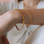 Gold plated stainless steel herringbone bracelet stacked with a rope-chain bracelet on a model's wrist.