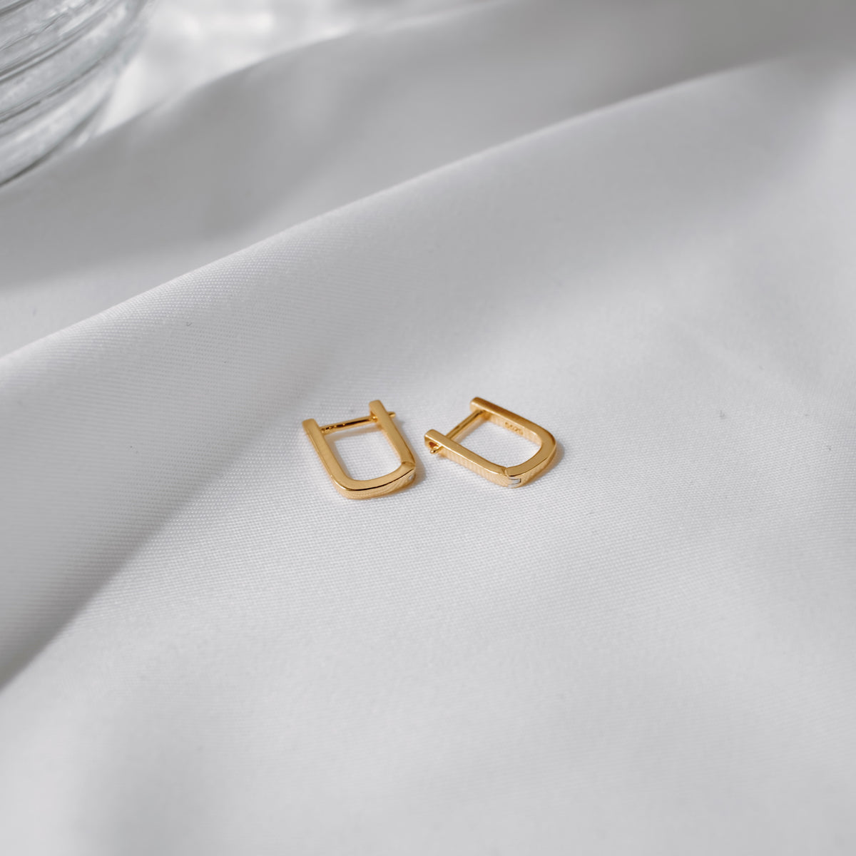 Pair of Tiny Oval Hoops in 18K gold vermeil on white silk.