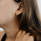Gold plated stainless steel classic hoop on a model's ear.