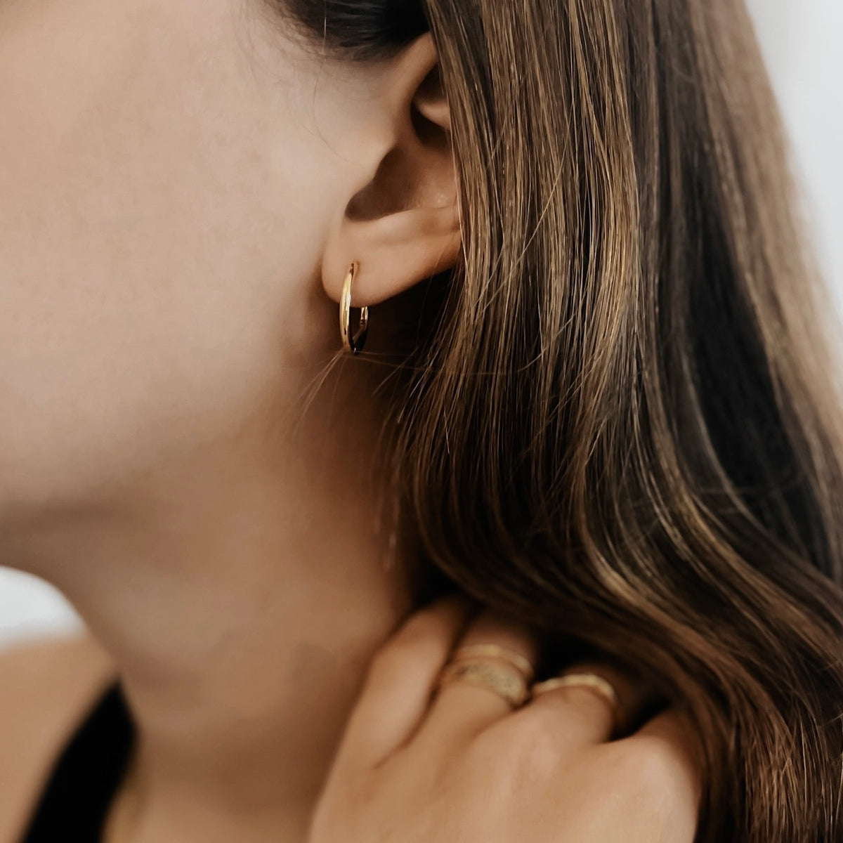 Gold plated stainless steel classic hoop on a model's ear.