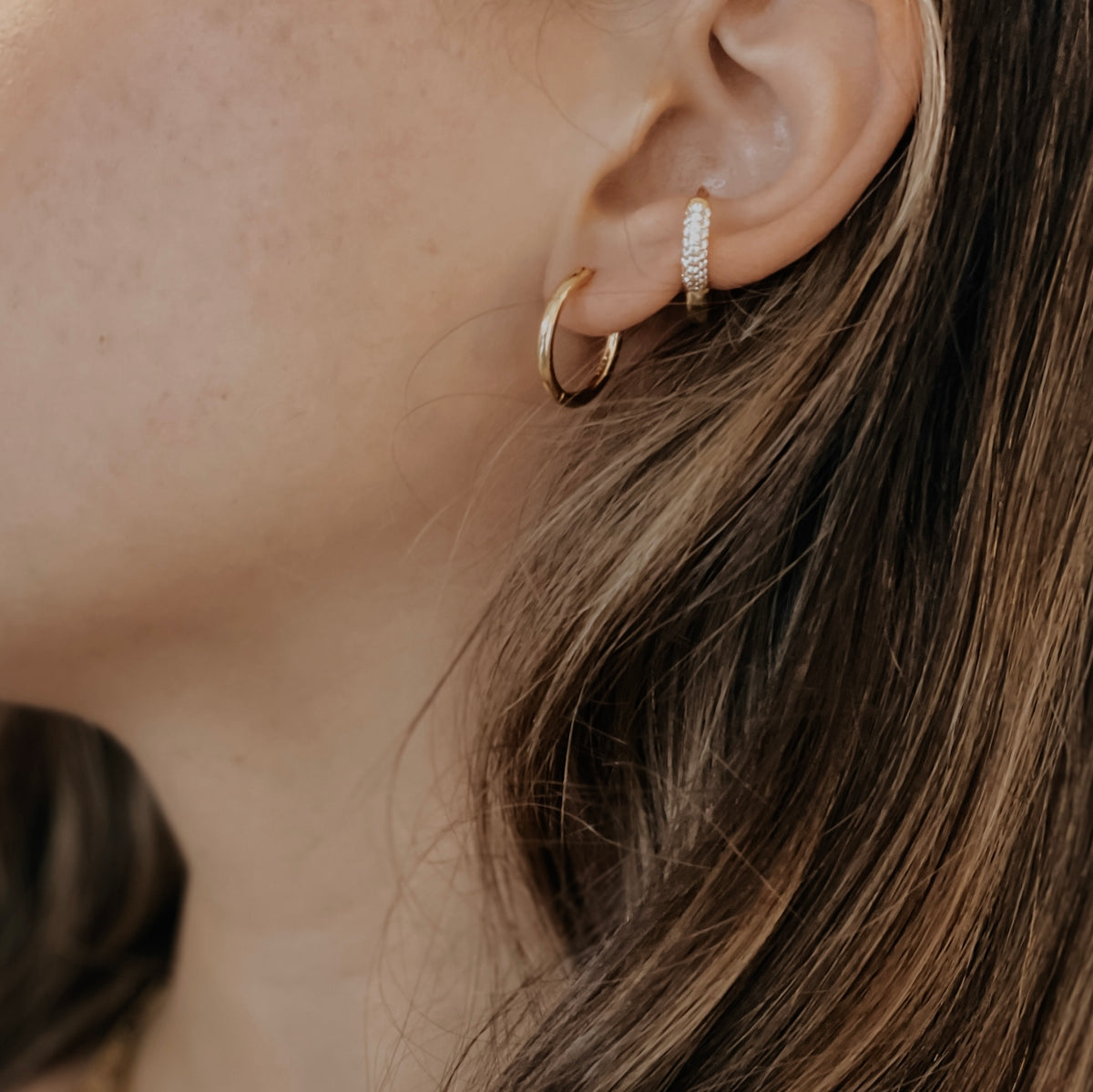 Gold plated stainless steel classic hoop on a model's ear.
