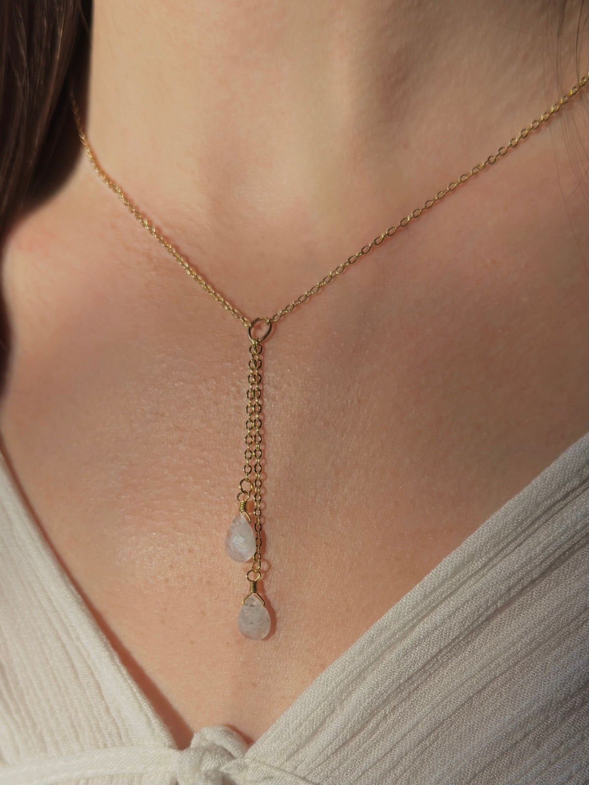 Rainbow moonstone lariat necklace in gold filled on a model, a Y-drop ending in two moonstone teardrops.