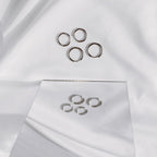 Silver-tone stainless steel classic hoops on white fabric with a mirror reflection.