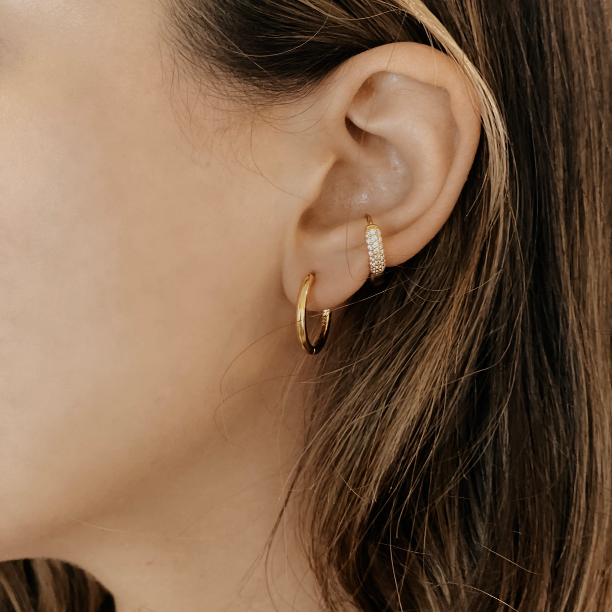 Gold plated stainless steel classic hoop stacked with a pave huggie on a model's ear.
