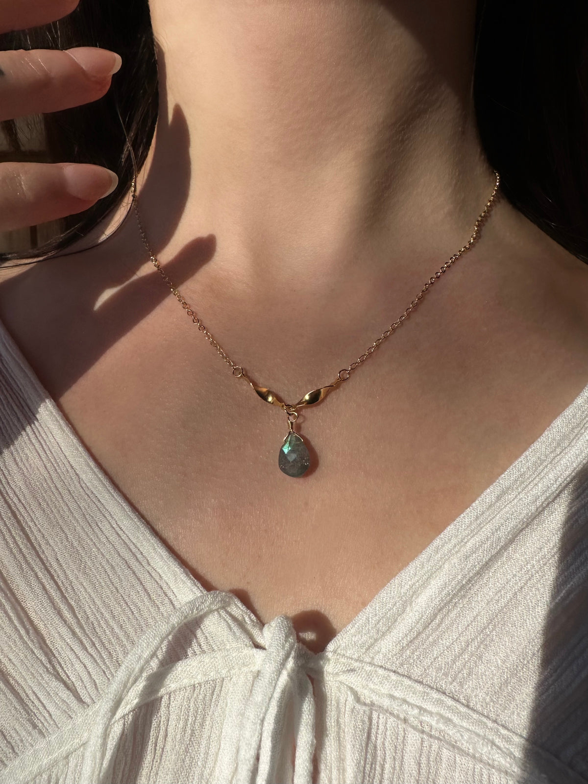 Labradorite drop necklace in gold filled on a model, a grey-blue labradorite teardrop on a fine chain.