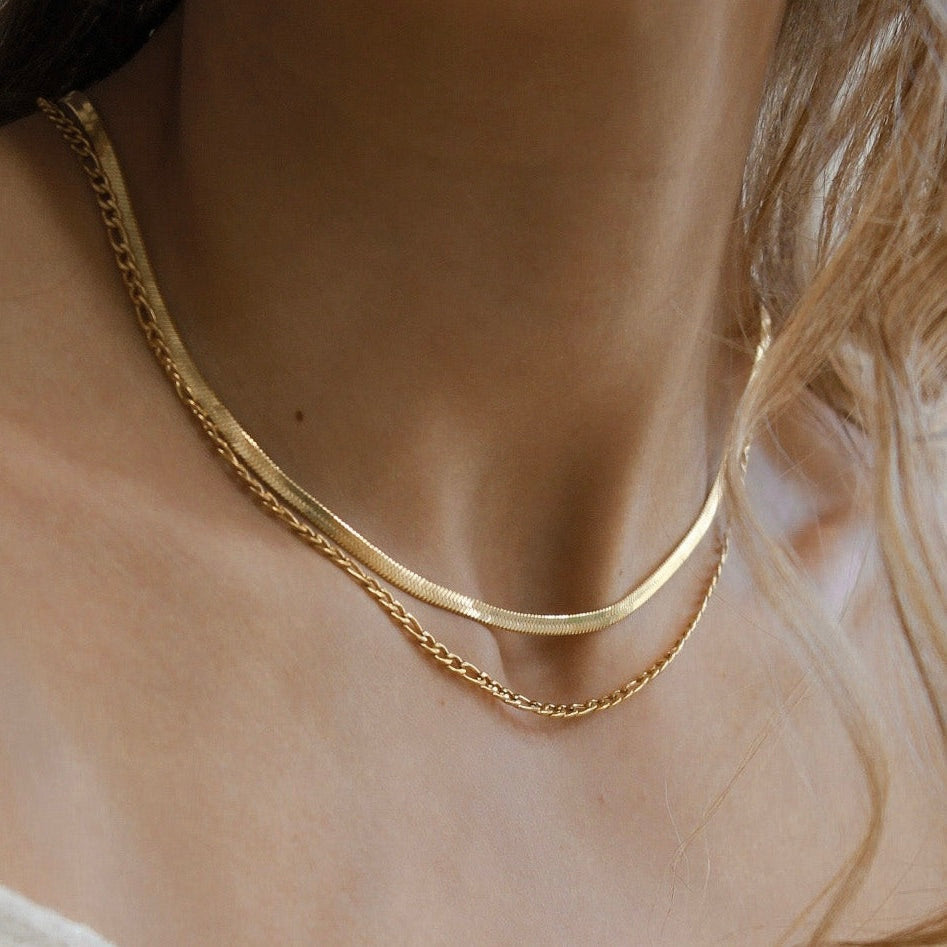 Clementine herringbone chain in gold plated stainless steel layered with a rope chain on a model.