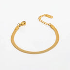 Clementine flat herringbone bracelet in gold plated stainless steel, coiled to show the lobster clasp and extender chain.