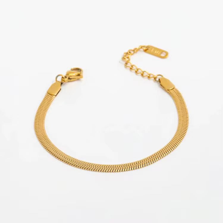Clementine flat herringbone bracelet in gold plated stainless steel, coiled to show the lobster clasp and extender chain.