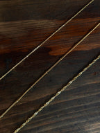 Gold filled Wave chain with twisted, wave-like detailing on a wooden surface.