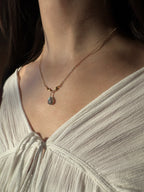 Labradorite teardrop necklace in gold filled on a model in sunlight.