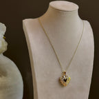 Large Heart locket on a satellite chain, shown on an ivory bust beside a white vase.