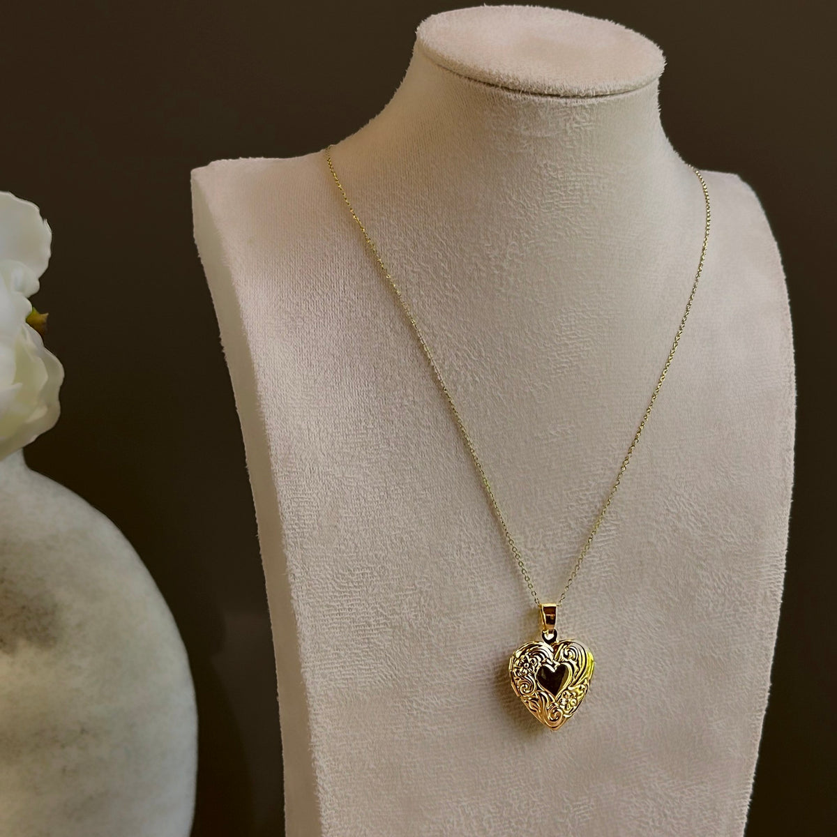 Large Heart locket on a satellite chain, shown on an ivory bust beside a white vase.