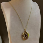 Large Oval locket with an ornate engraved frame, on a fine satellite chain on an ivory bust.