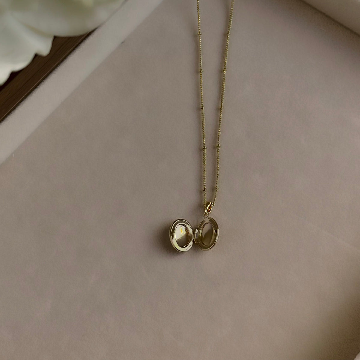 Oval locket open on a linen tray, showing both photo windows.