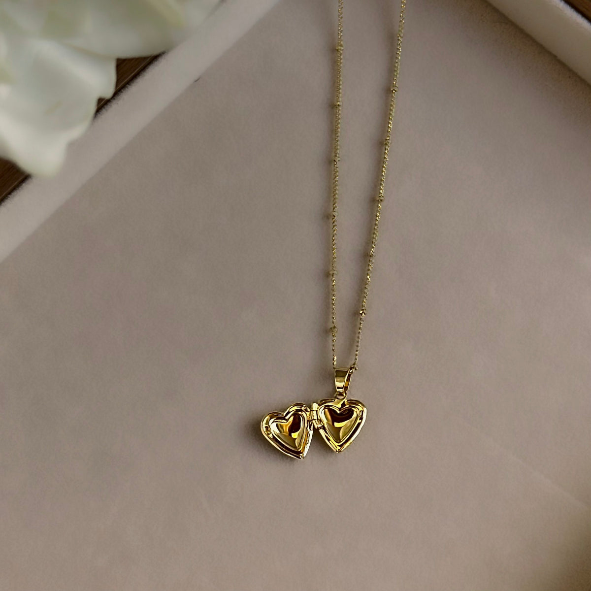 Small Heart locket open on a linen tray, showing both photo windows.