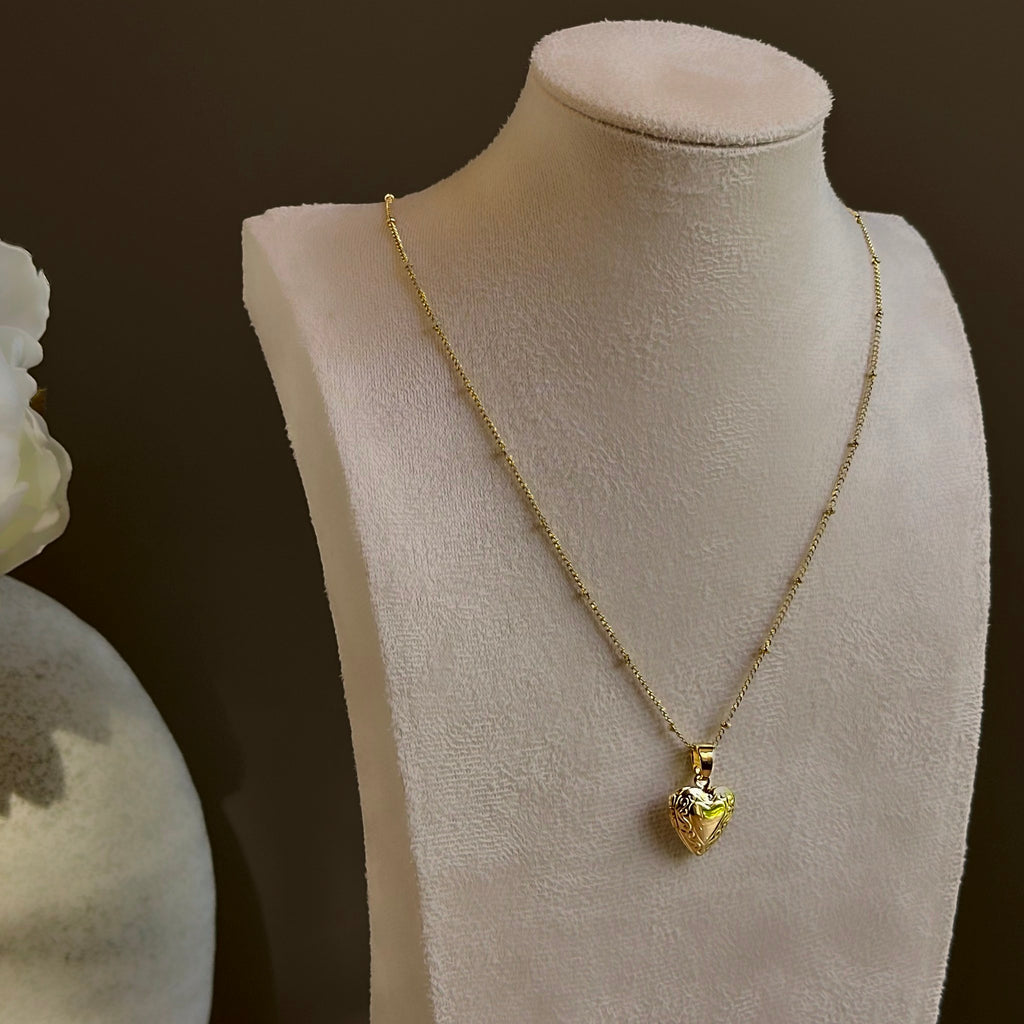 Small Heart locket on a satellite chain, shown on an ivory bust beside a white vase.