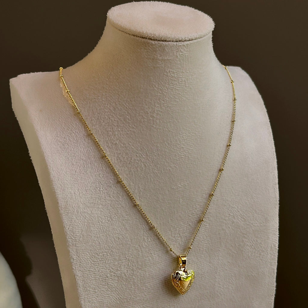 Small Heart locket, a puffed heart on a fine satellite chain, on an ivory bust.