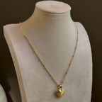Small Heart locket, a puffed heart on a fine satellite chain, on an ivory bust.