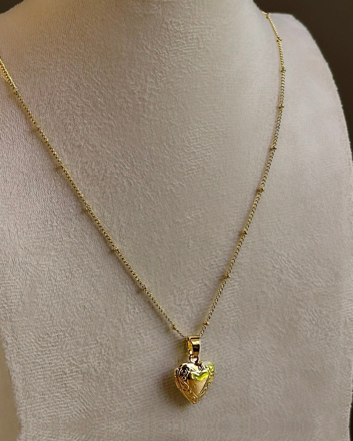 Small Heart locket, a puffed heart on a fine satellite chain, on an ivory bust.