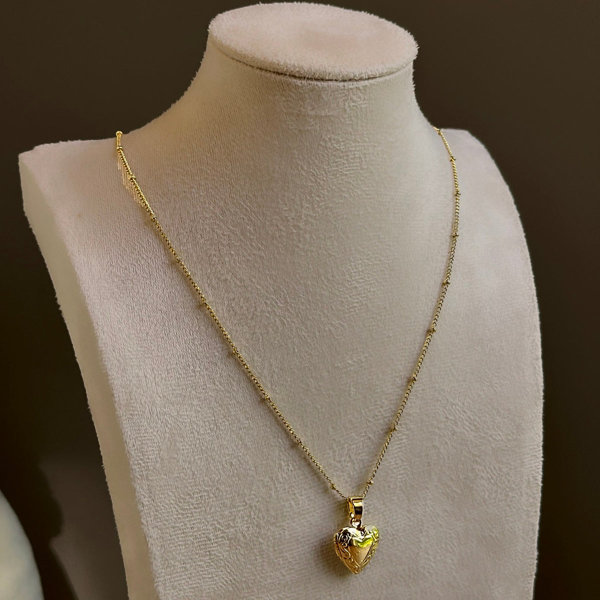 Small Heart locket, a puffed heart on a fine satellite chain, on an ivory bust.