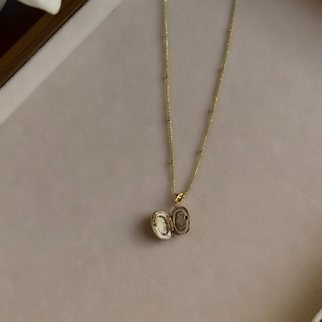 Small Ornate Oval locket open on a linen tray, showing both photo windows.