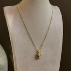 Small Ornate Oval locket with a pearl charm hanging beside it, on an ivory bust.