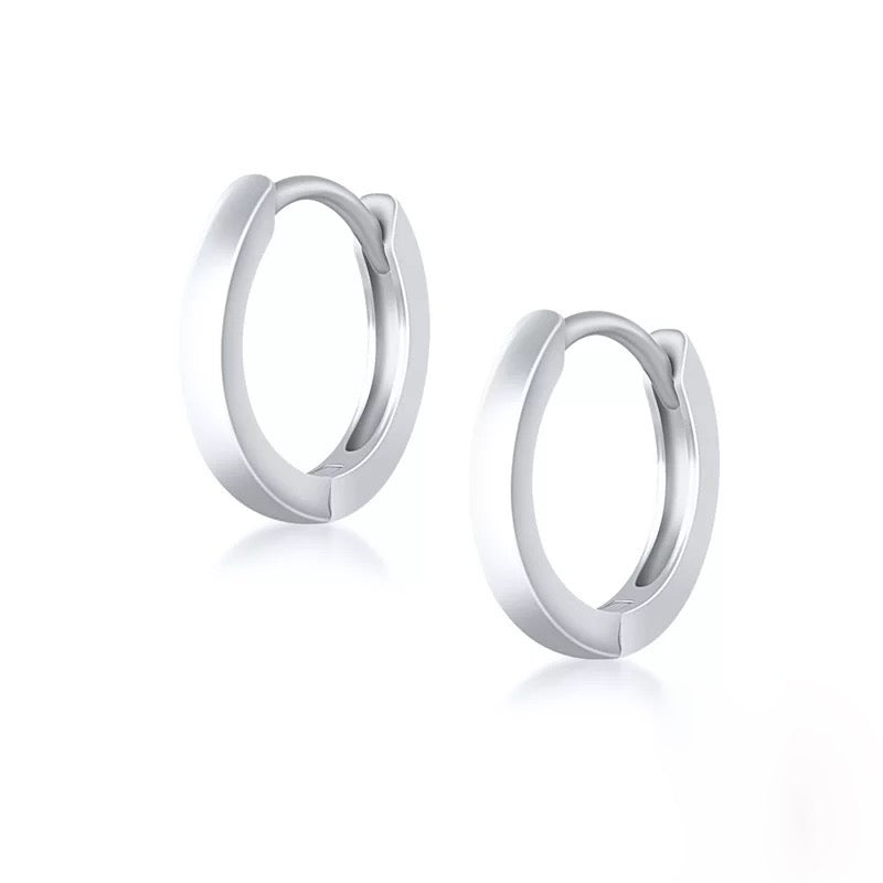 Pair of sterling silver classic huggie hoops on a white background.